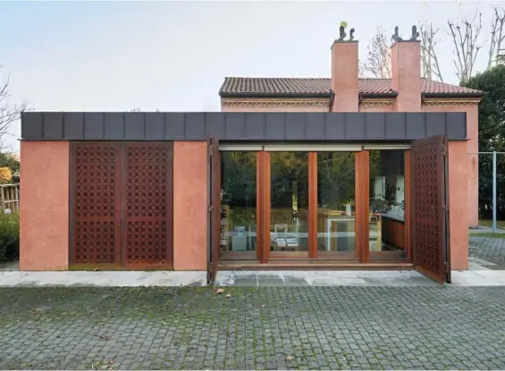  ?? ?? L’esterno della casa è colorato di rosso. I serramenti di sicurezza in Corten con incisione laser, su disegno di Scarpa, ricordano i mandolati dei vecchi fienili