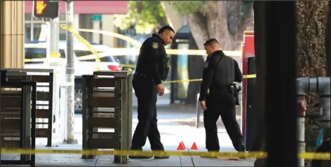  ?? ASSOCIATED PRESS ?? Sacramento Police officers look over evidence markers, in the early morning hours of Monday, near the scene of a fatal shooting outside of a downtown Sacramento night club.