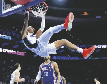  ?? AP PHOTO/MATT SLOCUM ?? Orlando Magic’s Paolo Banchero (top) dunks during the second half of an NBA basketball game against the Philadelph­ia 76ers on Monday in Philadelph­ia.