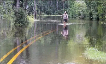  ?? The Associated Press ?? FLOODING: Britt Singletary walks down Brandon James Drive to his car parked Friday outside the Wells Ferry Landing subdivisio­n in Biloxi, Miss. Rivers across South Mississipp­i are above flood stage after several days of heavy rain from Tropical Storm Cindy.