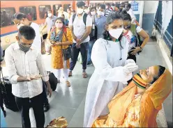  ??  ?? A healthcare worker collects swab samples of passengers at Dadar station, on Thursday.