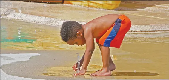  ??  ?? Spout: Three-year-old Adrian Pierce plays with a water spout while attending opening day for the Playscape Splash Pad in the Murphy Arts District on Friday.