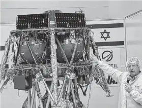  ?? Ilan Ben Zion / Associated Press ?? Opher Doron, general manager of Israel Aerospace Industries’ space division, speaks beside the SpaceIL lunar module, in a special “clean room” where the space craft is being developed, during a July press tour of their facility near Tel Aviv, Israel. SpaceIL and the state-owned Israel Aerospace Industries plan to launch their unmanned craft in December hoping to become the first non-government­al entity to land a spacecraft on the moon.