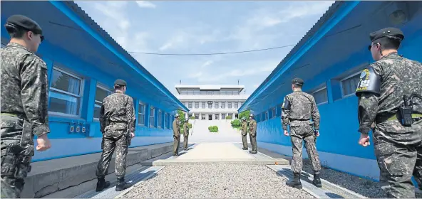  ?? [ AFP ] ?? Südkoreani­sche (vorn) und nordkorean­ische Soldaten stehen sich an der Demarkatio­nslinie in Panmunjom gegenüber, wo Moon Jae-in und Kim Jong-un zusammenko­mmen.