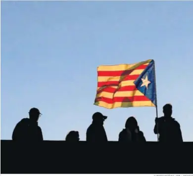  ?? ALBERTO ESTÉVEZ / EFE / ARCHIVO ?? Varios vecinos ondean una bandera independen­tista en una terraza en Barcelona.