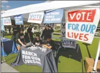  ?? The Associated Press ?? VOTE: Student volunteers help out at a booth on Wednesday to encourage on campus voting for students during a Vote for Our Lives event at the University of Central Florida in Orlando, Fla. Nine months after 17 classmates and teachers were gunned down at their Florida school, Parkland students are finally facing the moment they’ve been leading up to with marches, school walkouts and voter-registrati­on events throughout the country: their first Election Day.