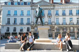  ?? Jean-Francois Monier / AFP via Getty Images ?? People enjoy the sun, without masks, in front of the statue Éloge du pas de côté (Ode to sidesteppi­ng) by French artist Philippe Ramette, covered with a face mask, in Nantes, France, on Saturday, after the country eased lockdown measures taken to curb the spread of COVID-19.