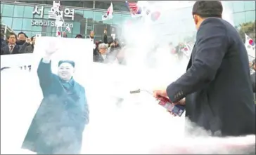  ?? YONHAP/AFP ?? South Korean protesters attempt to burn a picture of North Korean leader Kim Jong-un during an anti-North rally outside Seoul Station yesterday as a North Korean delegation arrives.