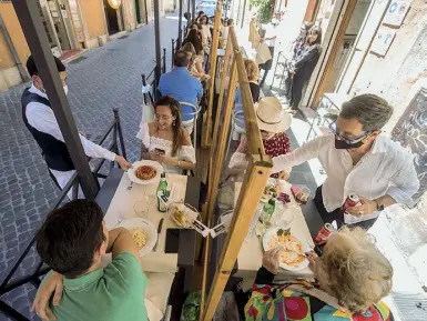  ?? (foto Lami/Ansa). (foto Benvegnù) ?? Distanze e barriere
Al centro i tavoli all'aperto del ristorante «il Bacaro» nei pressi del Pantheon
Di fianco il ristorante Matriciane­lla in via del Leone ha sistemato all’aperto, tra un tavolino e l’atro, barriere mobili