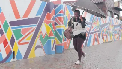  ?? Picture: Tracy Lee Stark ?? SMILING IN THE RAIN. A woman walks during a shower in Soweto yesterday. Most parts of Johannesbu­rg have had rain all week and more downpours are expected over the weekend.