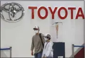  ?? ?? People walk past the logo of Toyota at a showroom in Tokyo Monday, Oct. 18, 2021. Toyota’s profit declined 31% in the January-March 2022 quarter from the year before, but the Japanese automaker still wrapped up a year of record earnings. (AP)