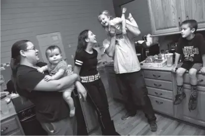  ??  ?? The Echelmeier­s gather before dinner in the kitchen of their new home in Lakewood on Nov. 9. The large, extended family had a series of mishaps that left them homeless. Helen H. Richardson, The Denver Post