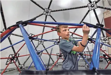  ?? See more photos at jsonline.com/news. PHOTOS BY ANGELA PETERSON/MILWAUKEE JOURNAL SENTINEL ?? Josh Larsen, 8, of Franklin works in the Geodesic Dome on Saturday at the Maker Faire at State Fair Park. Andrew Cegielski, a representa­tive of MKE Domes, said putting together this structure is a teaching tool that gives children a chance to have fun...