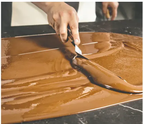  ?? OMAR TORRES / AFP VIA GETTY IMAGES ?? The tempering process sees a chocolatie­r melt chocolate in a bain marie (hot water bath), pour most of it onto marble, agitate it as it cools and thickens, and then combine it with the remaining melted chocolate.