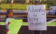  ??  ?? Stella Rodriguez, 4, and her sister Hope Rodriguez, 7, hold up signs during the rally.