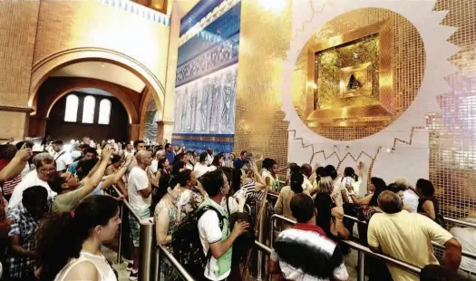  ?? Rivaldo Gomes/Folhapress ?? Fiéis adoram imagem de Nossa Senhora Aparecida na missa especial de coroação da Santa, ontem à noite, na Basílica de Aparecida; celebração contou com a participaç­ão de crianças vestidas de anjos e de casais com bandeiras dos Estados; Daniel cantou...