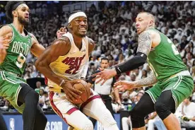  ?? LYNNE SLADKY / ASSOCIATED PRESS ?? Miami Heat forward Jimmy Butler (22) drives to the basket between Boston Celtics guard Derrick White (9) and center Daniel Theis during Game 1 of an Eastern Conference final Tuesday in Miami. Butler’s averaging 29.8 points, 7.7 rebounds, 5.4 assists and 2.3 steals in these playoffs on 53.5% shooting.