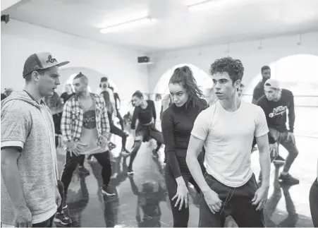  ??  ?? Paul Becker, left, directs Descendant­s stars Sofia Carson and Cameron Boyce, with some of the sequence’s backup dancers in the background, at a dance studio in Los Angeles.