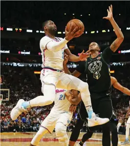  ?? (TNS) ?? MIAMI HEAT guard Dwyane Wade (with ball) drives to the basket against Milwaukee Bucks defender John Henson on Friday night in the Heat’s 91-85 home victory over the Bucks in Wade’s emotional first game back for the Heat after spending the first 13...