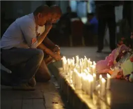  ?? AARON FAVILA, THE ASSOCIATED PRESS ?? A man holds back tears as he lights candles for victims in an attack at the Resorts World Manila complex, Friday in Manila, Philippine­s. Police say a man stormed a crowded Manila casino and used gasoline to set gambling tables on fire, creating clouds of smoke that swept through the crowds and killed at dozens of people.