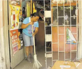  ??  ?? A shopowner sweeps up in front of her store in Anchovy yesterday following heavy rain and flooding throughout communitie­s on Friday.