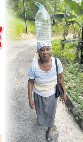  ?? IAN ALLEN ?? Emelyn Banton makes her way home after another of her daily trips to fetch water in Aberdeen square, St Elizabeth.