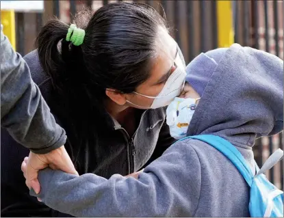  ?? MARK LENNIHAN / AP ?? Maria Flores kisses her son Pedro Garcia, 4, while a teacher takes his hand as he arrives for the first day of school at the Mosaic Pre-K Center in the New York City borough of Queens on Sept 21. The city’s public schools had delayed reopening for two weeks.