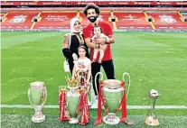  ??  ?? Honours: Mohamed Salah poses with his family at Anfield with (from left) the European Super Cup, Premier League trophy, European Cup and Club World Cup