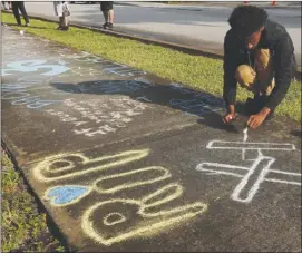  ?? The Associated Press ?? Lenar Nesmith, of Pompano Beach, Fla., a fan of rapper XXXTentaci­on, writes a message on the sidewalk,Tuesday outside Riva Motorsport­s in Deerfield Beach, Fla., where the troubled musician was killed the day before.