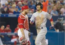  ?? Canadian Press photo ?? Boston Red Sox Mookie Betts (right) smiles as he crosses home plate in front of Toronto Blue Jays catcher Russell Martin after hitting a two run home run off Toronto Blue Jays starting pitcher Joe Biagini during sixth inning Major League baseball...