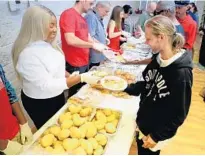  ??  ?? Imani Dennis, of Church by the Glades, serves a roll to Tracy Moore, 34, at a Christmas Eve dinner for the homeless at at St. Christophe­r’s Episcopal Church in Fort Lauderdale.