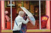  ?? (AP/The Times-Picayune/The New Orleans Advocate/Max Becherer) ?? A couple shelter from the wind Tuesday during severe weather as they walk on Frenchmen Street in New Orleans.