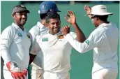  ??  ?? Herath being congratula­ted by his team-mates