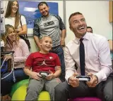  ?? AL DIAZ/MIAMI ?? David Beckham plays a soccer video game with patient Luis Rayo, 9, as Beckham visits children being treated for cancer at Nicklaus Children’s Hospital on July 11.