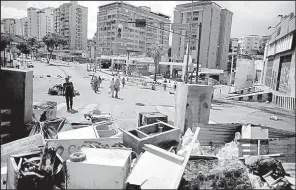  ?? AP/ARIANA CUBILLOS ?? People walk Saturday near a barricade erected by anti-government demonstrat­ors in the Petare neighborho­od of Caracas, Venezuela.