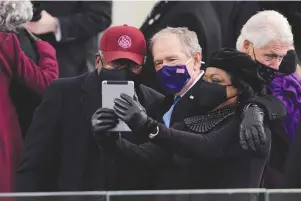  ?? The Associated Press ?? Q House Majority Whip James Clyburn of South Carolina, and former President George Bush, take a selfie before the 59th Presidenti­al Inaugurati­on at the U.S. Capitol in Washington on Wednesday.