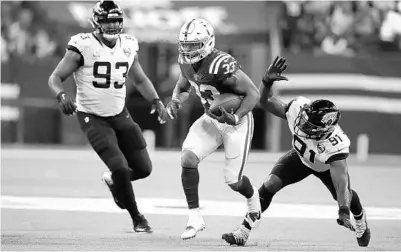  ?? MICHAEL CONROY/AP ?? The Colts’ Jonathan Williams (33) runs past the Jaguars’ Yannick Ngakoue (91) during the Jags’ loss to the Colts Sunday in Indianapol­is.