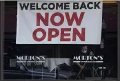  ??  ?? A sign reading “Welcome Back Now Open” is posted on the window of a Morton’s Steakhouse in San Francisco as a man works inside on Thursday.