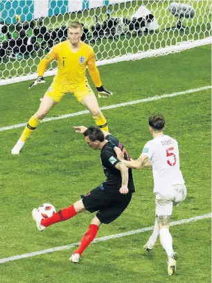  ?? PHOTO: GETTY IMAGES ?? The decisive blow . . . Mario Mandzukic scores Croatia’s winning goal past England goalkeeper Jordan Pickford despite the attentions of defender John Stones during the World Cup semifinal at Luzhniki Stadium in Moscow yesterday.