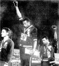  ?? — AFP photo ?? File photo shows US athletes Tommie Smith (centre) and John Carlos (right) raising their gloved fists in the Black Power salute to express their opposition to racism in the US during the their national anthem, after receiving their medals for first and third place along with second-placed Peter Norman (left) of Australia, in the men’s 200m event at the Mexico Olympic Games.