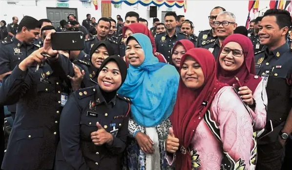  ??  ?? One for the album: Zuraida (blue headscarf) obliging a wefie with Fire and Rescue Department officers in Batu Kawan. — Bernama