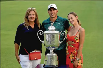  ?? ROSS KINNAIRD / GETTY IMAGES ?? A victorious moment: Brooks Koepka; his mother, Denise Jakows (left); and girlfriend Jena Sims with the Wanamaker Trophy on the 18th green following Koepka’s win Sunday in the 100th PGA Championsh­ip.