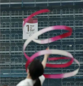  ?? Jae C. Hong The Associated Press ?? Former Japanese Olympic gymnast Kotono Tanaka performs Monday as a “1-Year to Go” banner hangs outside the Ariake Gymnastics Center in Tokyo. The games open July 24, 2020.