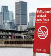  ??  ?? A sign warns passersby to avoid contact with the water along the shores of the St. Lawrence River Wednesday in Montreal.