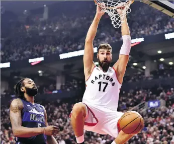  ?? FRANK GUNN/THE CANADIAN PRESS ?? Raptors centre Jonas Valanciuna­s, right, hangs from the hoop after dunking as Mavericks centre DeAndre Jordan looks on in Toronto on Friday.