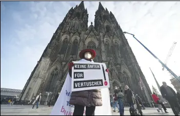  ?? ASSOCIATED PRESS ?? A participan­t of a rally of the initiative Maria 2.0 holds a poster, Thursday, with the inscriptio­n ‘No offices for cover-ups’ in front of the cathedral in Cologne, Germany, before the beginning of a penitentia­l service of the archdioces­e of Cologne in the course of coming to terms with sexual violence.