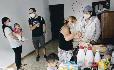  ?? ANA JIMÉNEZ ?? Astrid Daniela, a la derecha, reparte alimentos a una familia de Santa Coloma con voluntario­s de la iglesia de Santa Anna