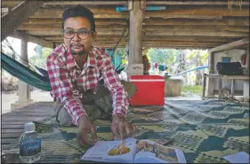  ?? (AP/Gemunu Amarasingh­e) ?? Vannak Anan Prum, who was double trafficked, points to his illustrati­on of an abusive former boss, a palm oil estate owner, in his graphic novel depicting his life as a slave on a fishing boat before being sold onto a Malaysian palm oil plantation, at his home in Pursat, Cambodia.