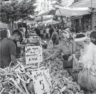  ?? Nicole Tung / New York Times ?? People shop at the market in Istanbul’s Fatih district. Turkey remains stuck in proximity to economic crisis, as households and businesses defer spending and investment in the face of weak growth.