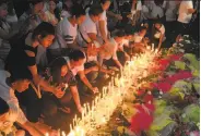  ?? Todd Pitman / Associated Press ?? Mourners light candles at a memorial to victims of the attack on the Resorts World Manila complex.